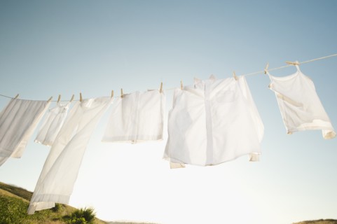 Laundry hanging on clothesline against blue sky.