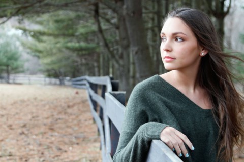 USA, New Jersey, Califon, Teenage girl (16-17) standing near fence and looking away, portrait.
