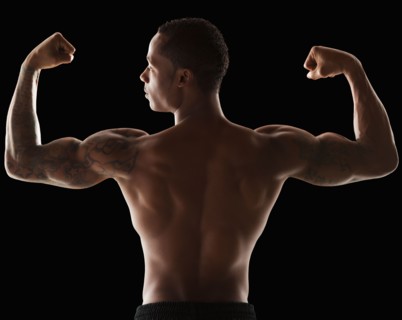 Rear view of muscular man flexing muscles. Photo : Mike Kemp