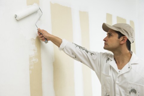 Man painting wall white.