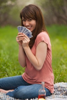 Young woman playing cards in orchard. Photo : Mike Kemp