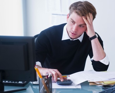 Man doing calculations holding head in hands. Photo : Daniel Grill