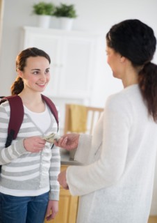 Mother giving money to teenage daughter (14-15).