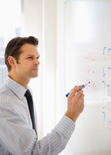 Businessman writing on whiteboard.