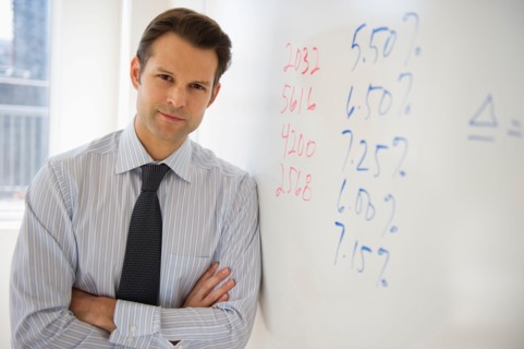 Portrait of businessman leaning against whiteboard.