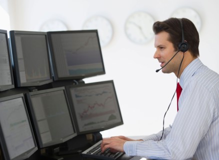Financial worker analyzing data displayed on computer screen.