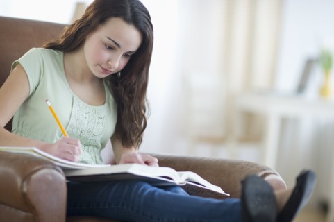 Portrait of teenage girl (14-15) doing homework.
