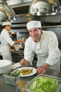 Chef and cook preparing food in commercial kitchen.