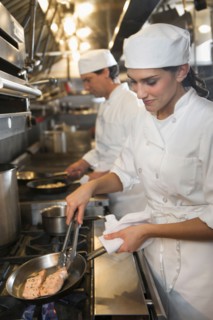 Chef and cook preparing food in commercial kitchen.