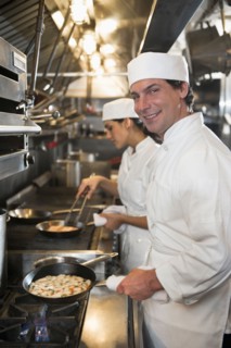 Chef and cook preparing food in commercial kitchen.