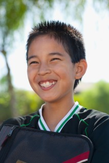 School boy (12-13) with bag, smiling. Photo : Noah Clayton