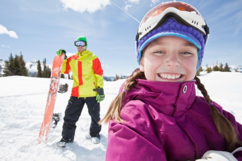 USA, Colorado, Telluride, Father and daughter (10-11) posing with snowboards in winter scenery.