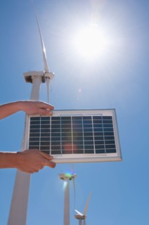 USA, California, Palm Springs, Woman's hands holding solar panel with wind turbines. Photo : Daniel