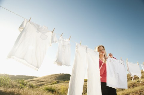 Woman hanging laundry on clothesline .