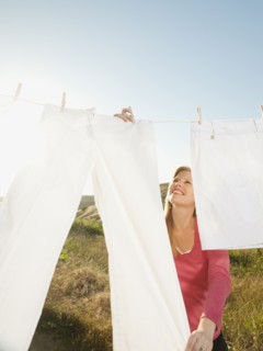Woman hanging laundry on clothesline .