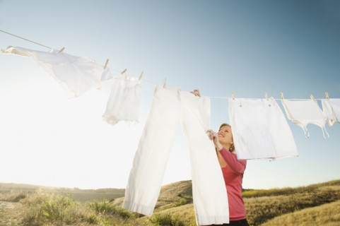 Woman hanging laundry on clothesline .