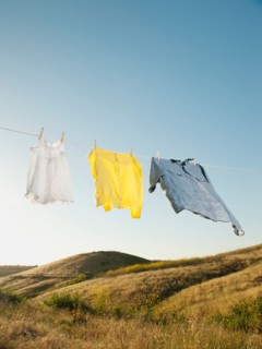 Laundry hanging on clothesline against blue sky.