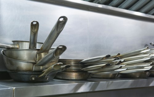 Close up frying pans on shelf in commercial kitchen.