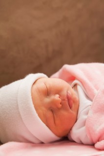 Baby girl (0-1 month) sleeping on sofa. Photo : Mike Kemp