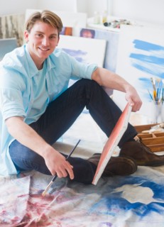Portrait of young man painting picture in studio. Photo : Daniel Grill