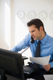 Businessman working on computer and talking on the phone.