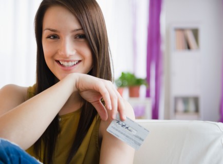 Portrait of smiling young woman holding credit card. Photo : Jamie Grill Photography