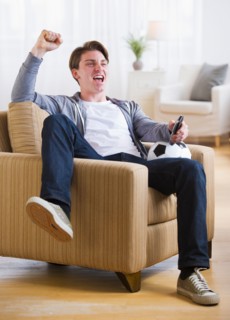 Man sitting in chair and watching TV soccer game. Photo : Daniel Grill