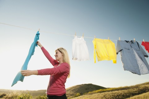 Woman hanging laundry on clothesline .