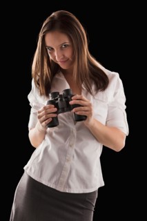 Young attractive businesswoman holding binoculars. Photo : Mike Kemp