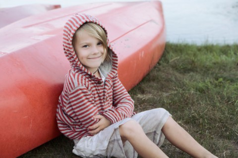 Portrait of boy (4-5) sitting by canoe. Photo : King Lawrence