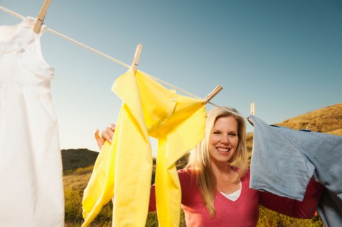 Woman hanging laundry on clothesline .