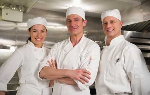 Three chefs posing in kitchen.