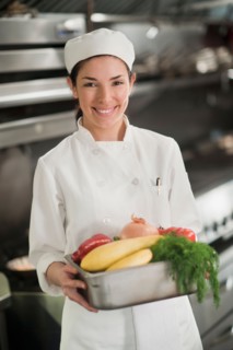 Smiling chef holding fresh vegetables.