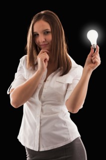Young attractive businesswoman holding illuminated bulb. Photo : Mike Kemp