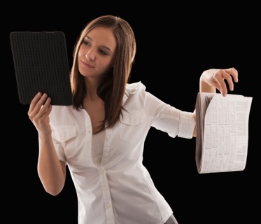 Young attractive businesswoman comparing financial results with financial column in newspaper.