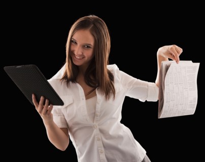 Young attractive businesswoman comparing financial results with financial column in newspaper.
