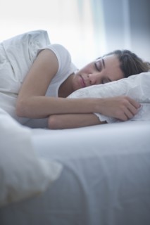 Happy young woman sleeping in bed.