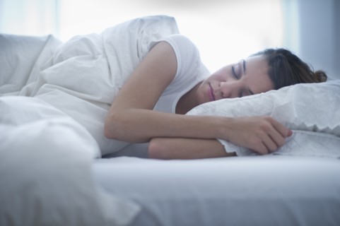 Happy young woman sleeping in bed.
