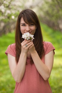 Young woman holding apple tree blossom in orchard. Photo : Mike Kemp