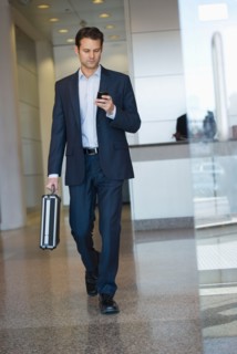 Businessman leaving office and using PDA.