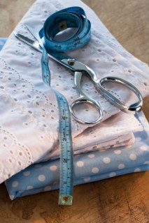 Close-up of folded textiles with scissors and tape measure.