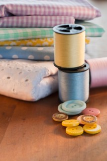 Close-up of thread, buttons and folded textiles.
