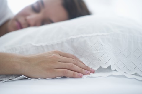 Happy young woman sleeping in bed.