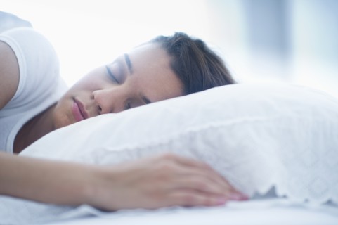 Happy young woman sleeping in bed.