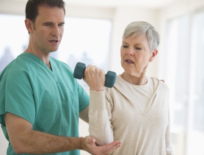 Man assisting  senior woman in weight lifting.