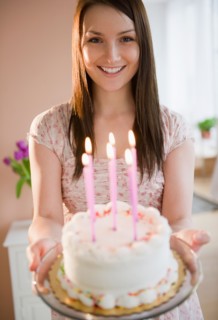 Young woman holding birthday cake. Photo : Jamie Grill Photography