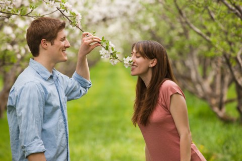 USA, Utah, Provo, Young couple smelling blossom in orchard. Photo : Mike Kemp