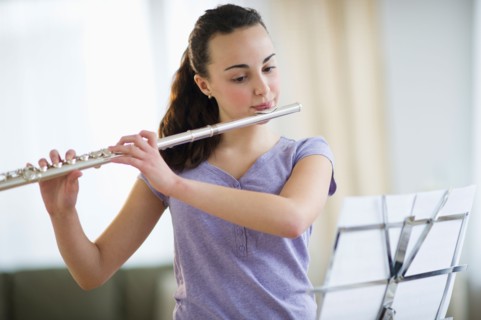 Teenage girl (14-15) playing flute .