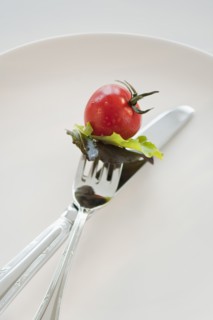 Cherry tomato and lettuce leaves on fork.