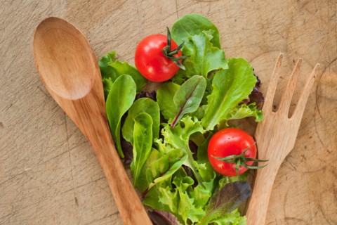 Salad leaves and wooden spoon and fork.